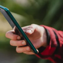 Mão segurando um celular ao entrar em contato com o escritório